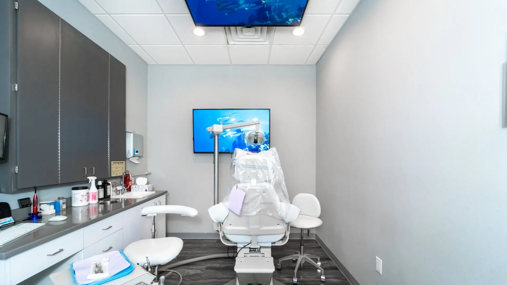 Bright dental operatory with patient chair and wall-mounted screens