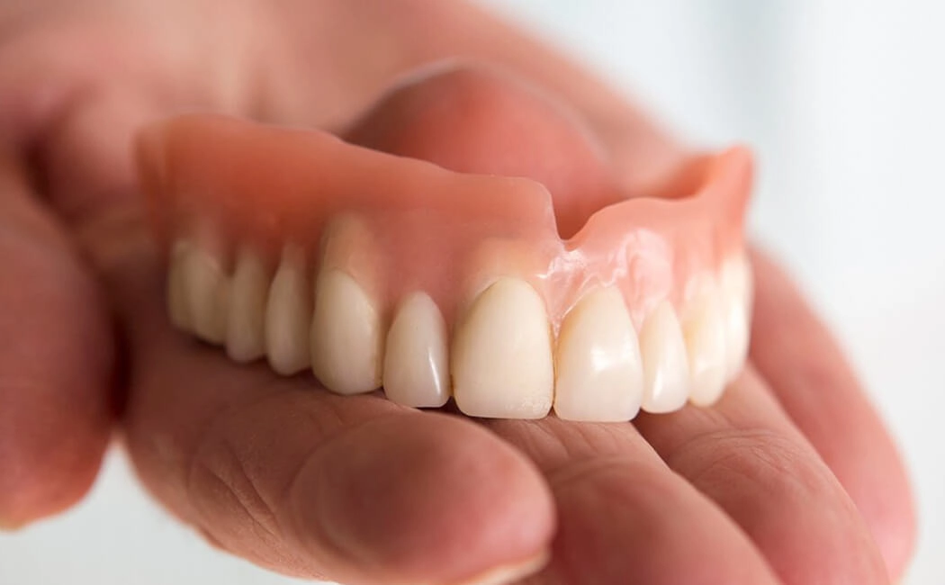 Close-up of a removable denture held between two hands