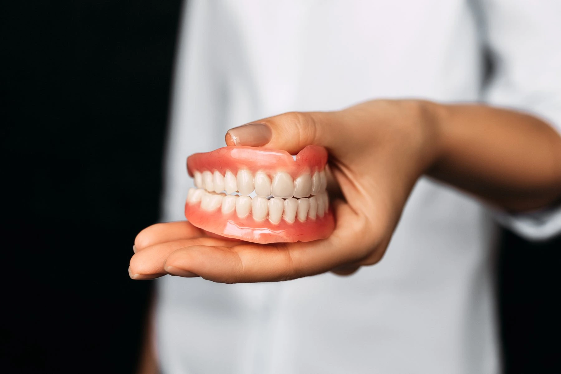 Dental professional holding a complete removable denture model